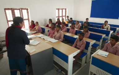 A teacher engaging with students in an under-resourced school, emphasizing the importance of quality education.